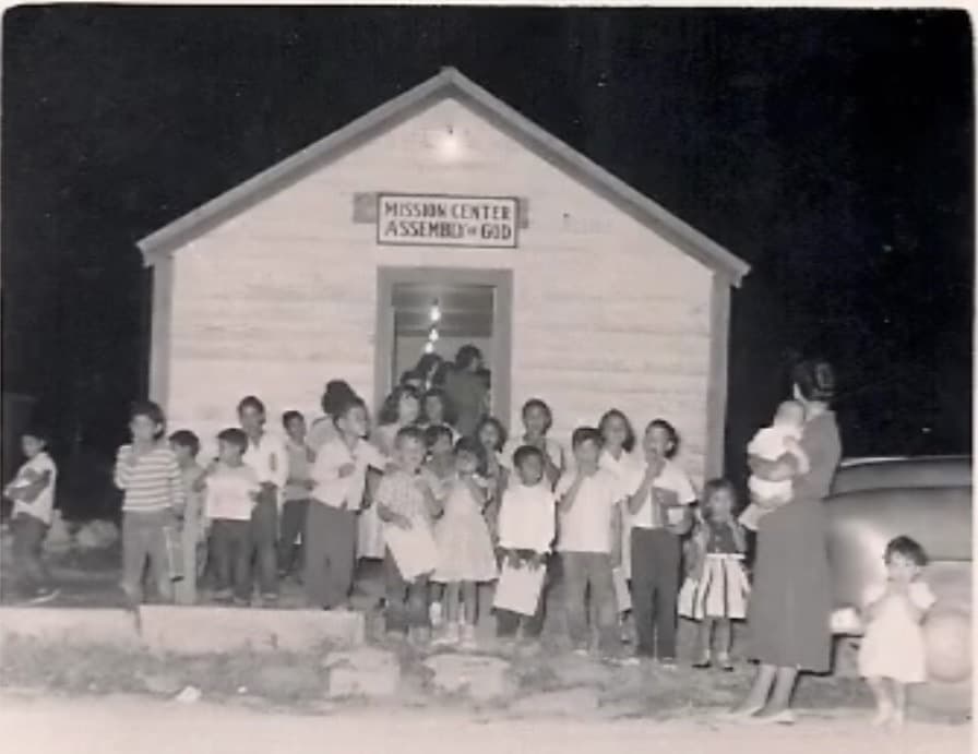 The first Mission Center Assembly of God building with families gathered outside